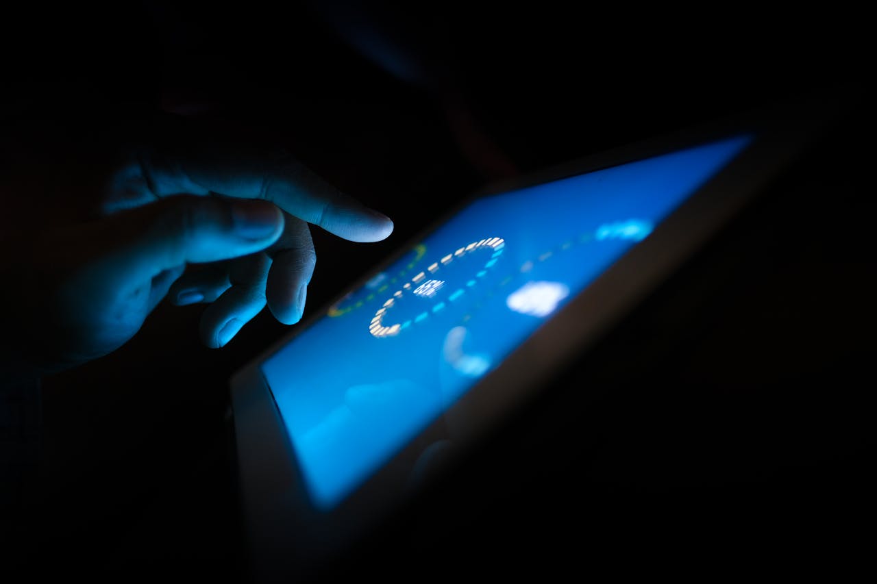 Services Close-up of a hand interacting with a glowing touchscreen in a dark setting, highlighting technology use.